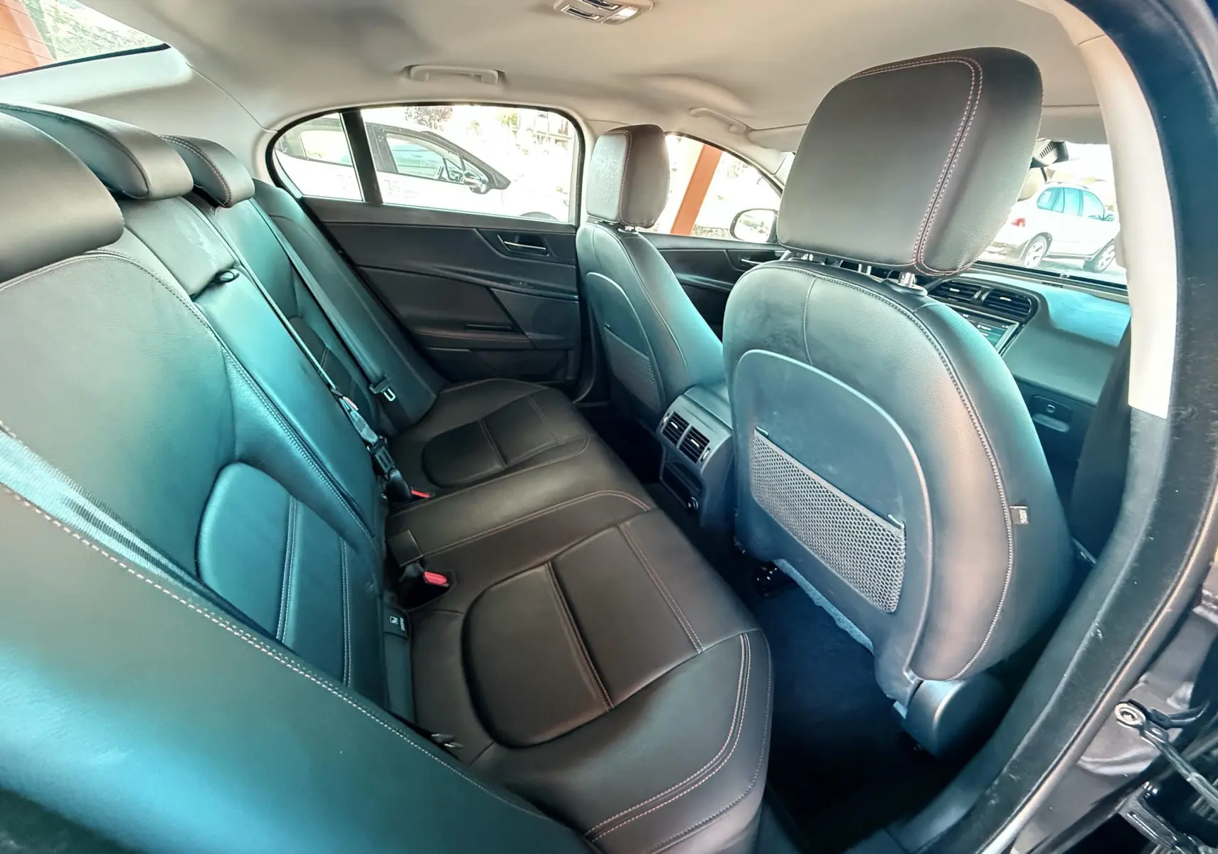 Vue intérieure arrière côté droit montrant les sièges en cuir noir et les finitions soignées d'une Jaguar XE 2019.