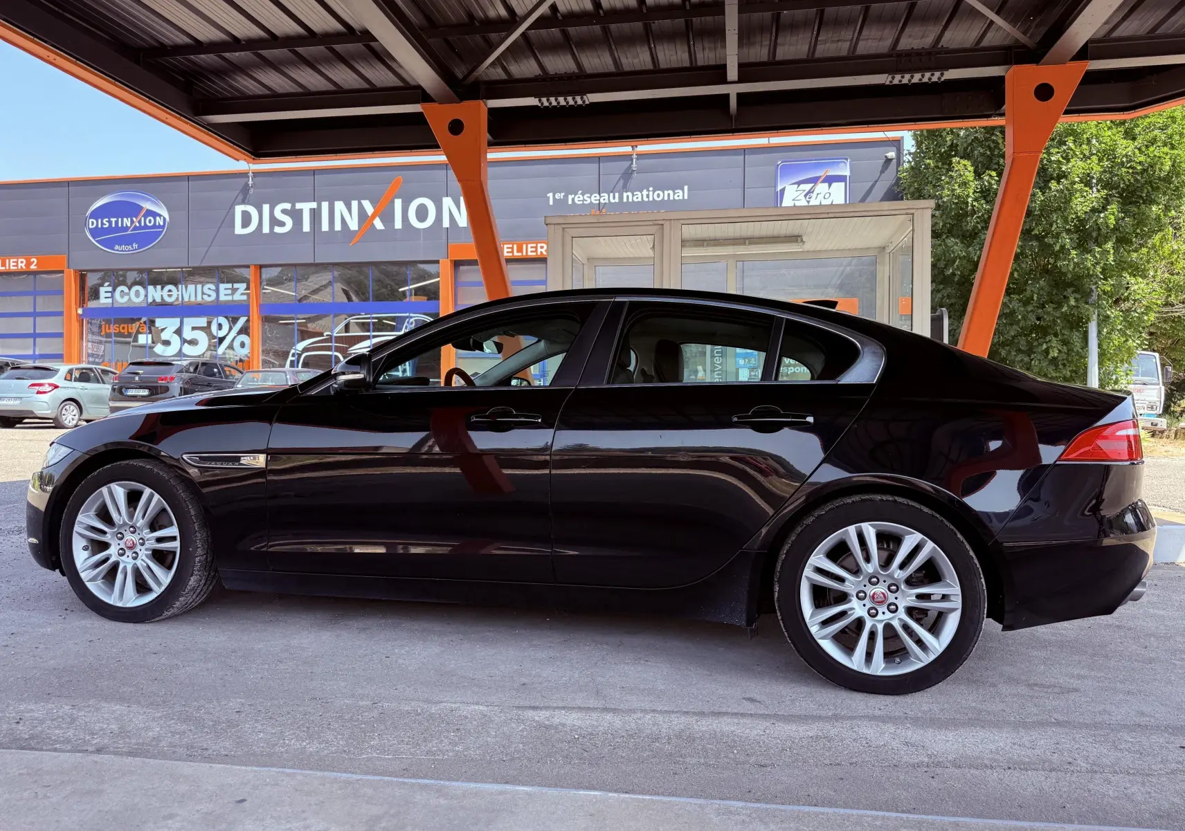 Profil côté gauche d'une Jaguar XE noire de 2019, sous un abri avec jantes alliage et lignes élégantes.