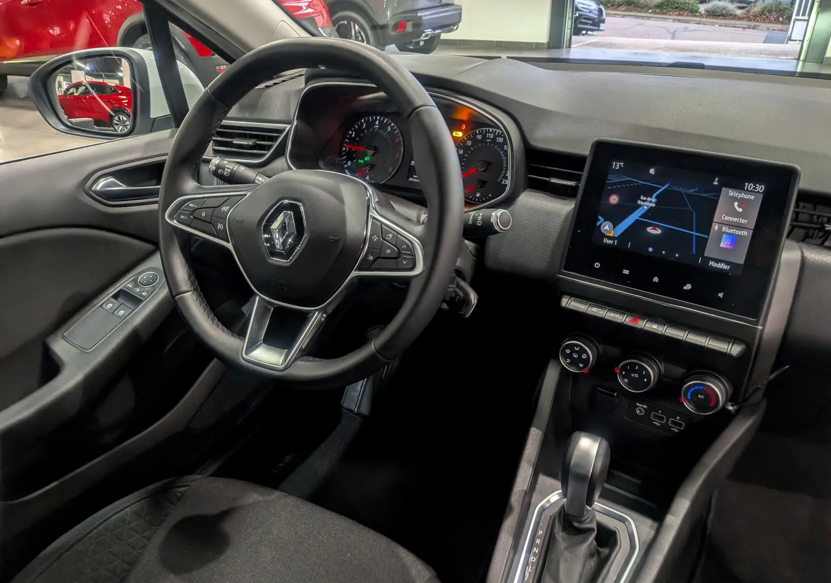 Vue intérieure côté conducteur de la Renault Clio V TCe 100 Business 2020, tableau de bord noir avec écran tactile et volant multifonction.