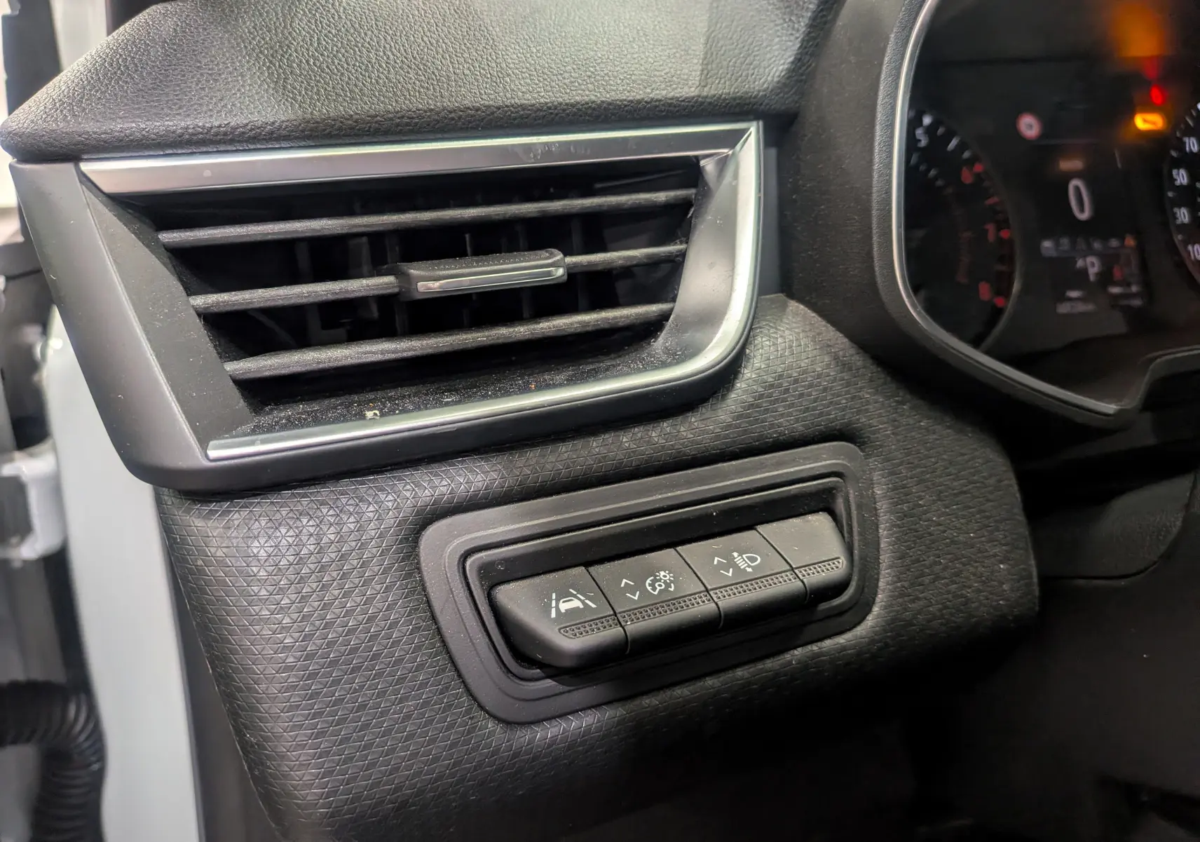 Détail intérieur côté gauche du tableau de bord de la Renault Clio V blanc glacier, avec commandes d’assistance et ventilation.