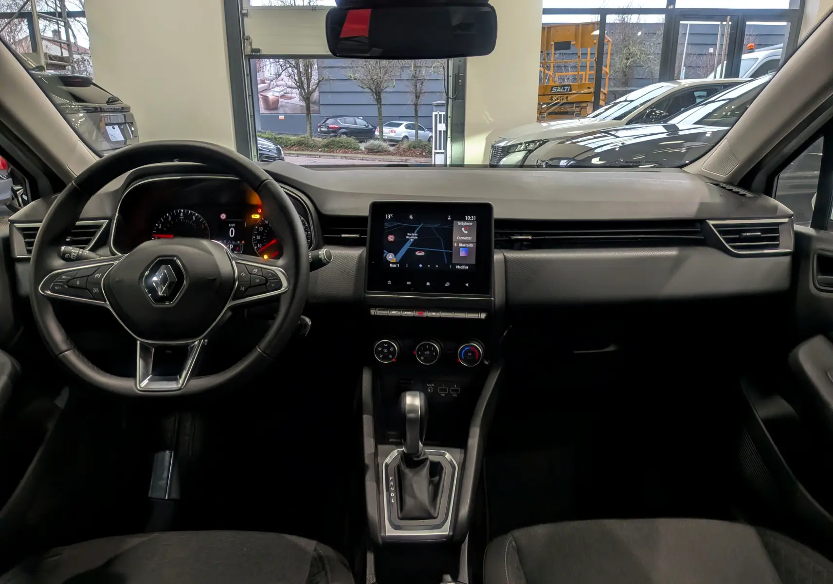 Vue intérieure avant de la Renault Clio V Business 2020, tableau de bord noir avec écran tactile central et volant multifonction.