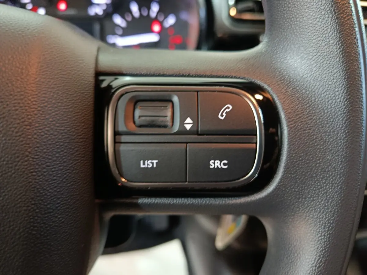 Gros plan sur les commandes gauche du volant noir de la Citroën C3 PureTech 83 BVM MAX 2024, avec boutons multifonctions.