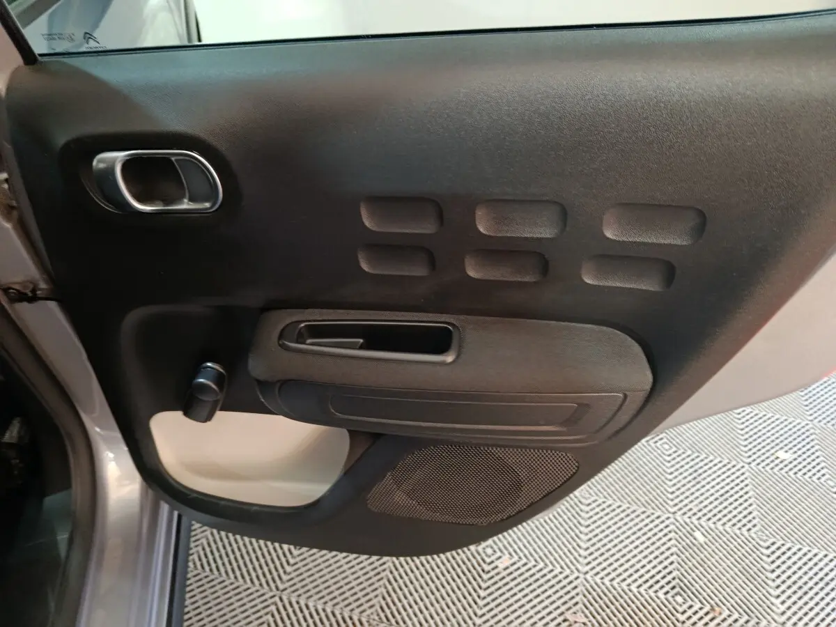 Vue intérieure de la porte avant gauche gris foncé de la Citroën C3 2024 avec poignée et commande de vitre manuelle.