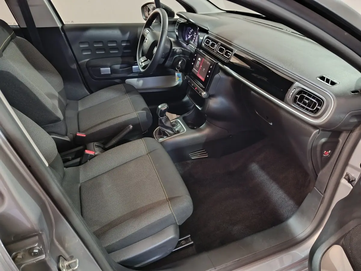 Vue intérieure côté conducteur de la Citroën C3 PureTech 83 BVM MAX 2024, sièges gris foncé et tableau de bord moderne.