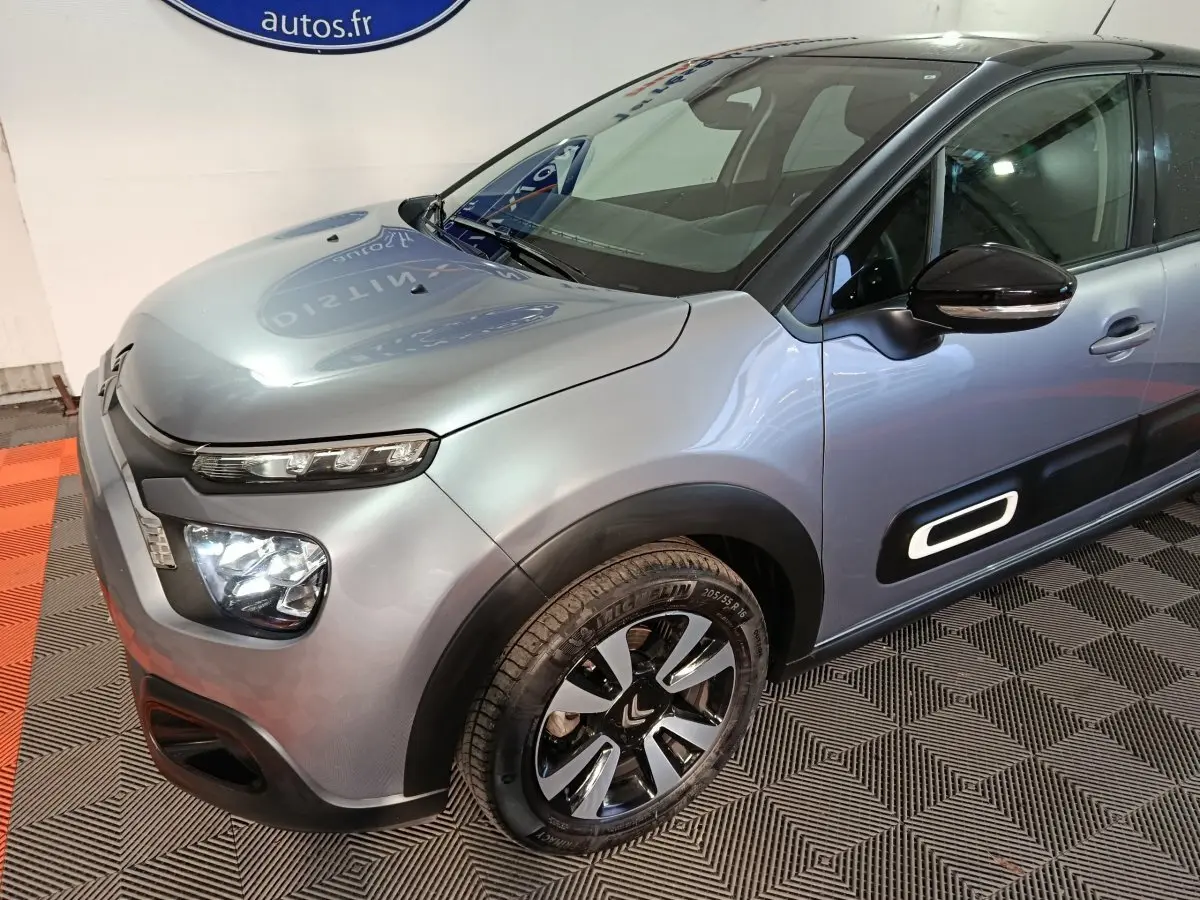Vue 3/4 avant droit d'une Citroën C3 gris foncé avec phares LED et protections latérales noires.