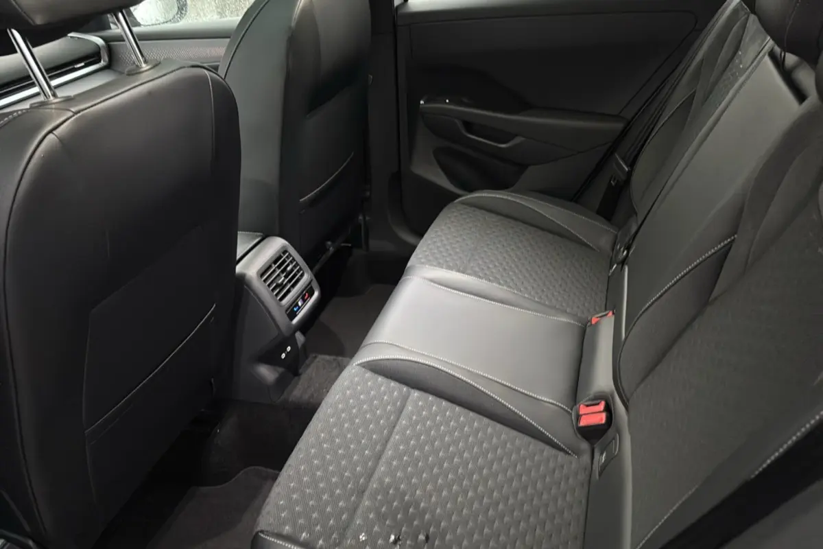 Vue intérieure arrière du Volkswagen T-Roc 2026, sièges tissu noir avec surpiqûres et aérateurs centraux visibles.