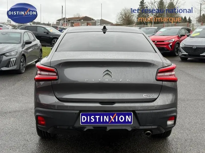 Vue arrière d'une Citroën C4 X gris 2024 avec feux LED distinctifs et logo centré sur un parking humide.