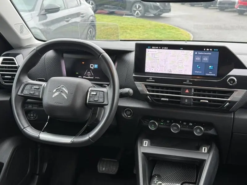 Vue intérieure du poste de conduite du Citroën C4 X gris 2024, avec volant multifonction et écran tactile central.