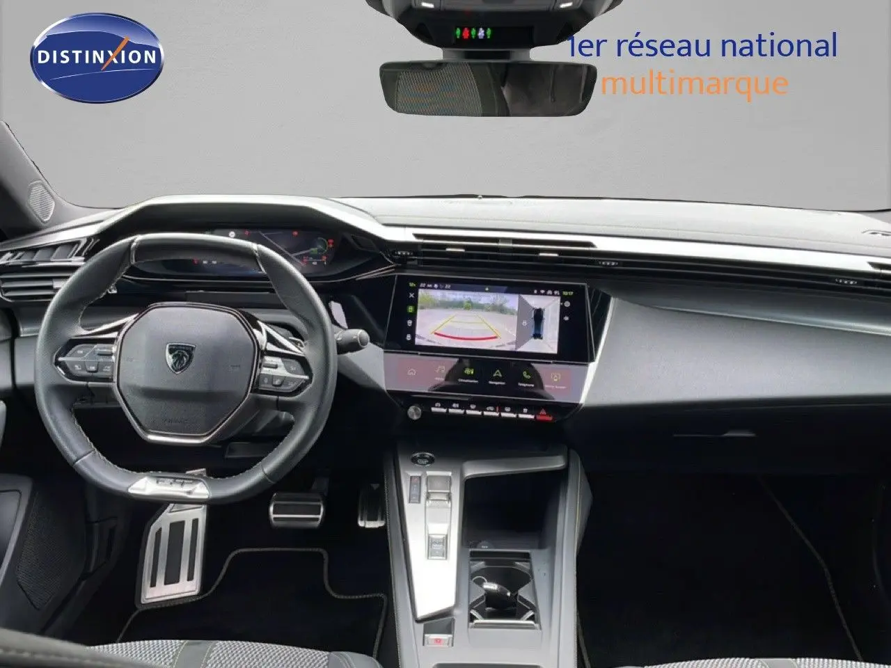 Vue intérieure frontale du tableau de bord et volant noir de la Peugeot 408 Hybrid 145ch avec écran tactile et caméra de recul affichée.