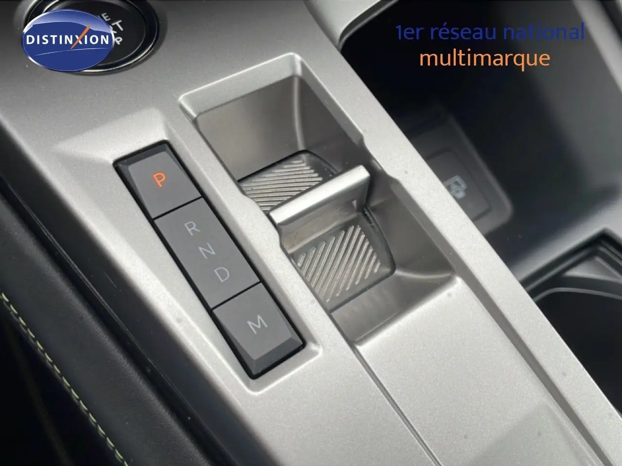 Gros plan sur la console centrale argentée avec sélecteur de boîte automatique et boutons de commande du Peugeot 408 Hybrid 2024 noir métal.