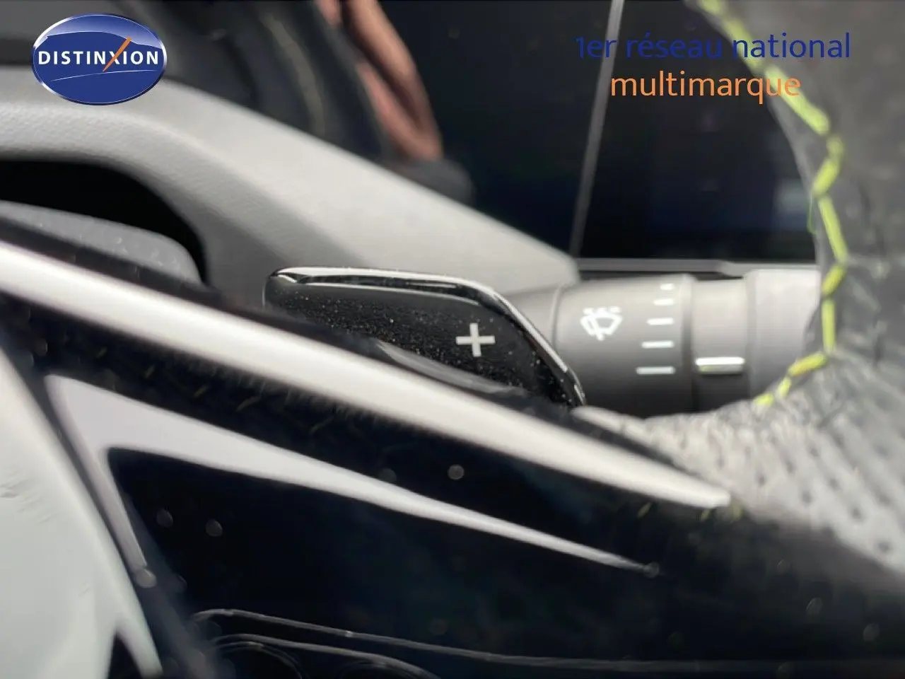 Gros plan sur la palette de changement de vitesse + du volant cuir noir avec surpiqûres jaunes dans une Peugeot 408 Hybrid 2024.
