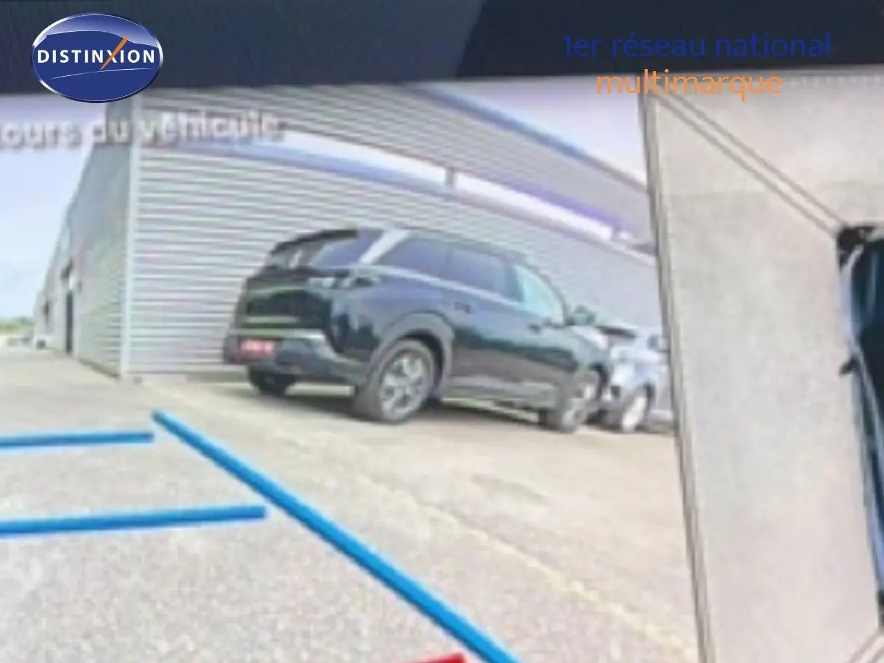 Vue 3/4 arrière d’un Peugeot 408 HYBRID 145CH GT noir métal stationné devant un bâtiment industriel.