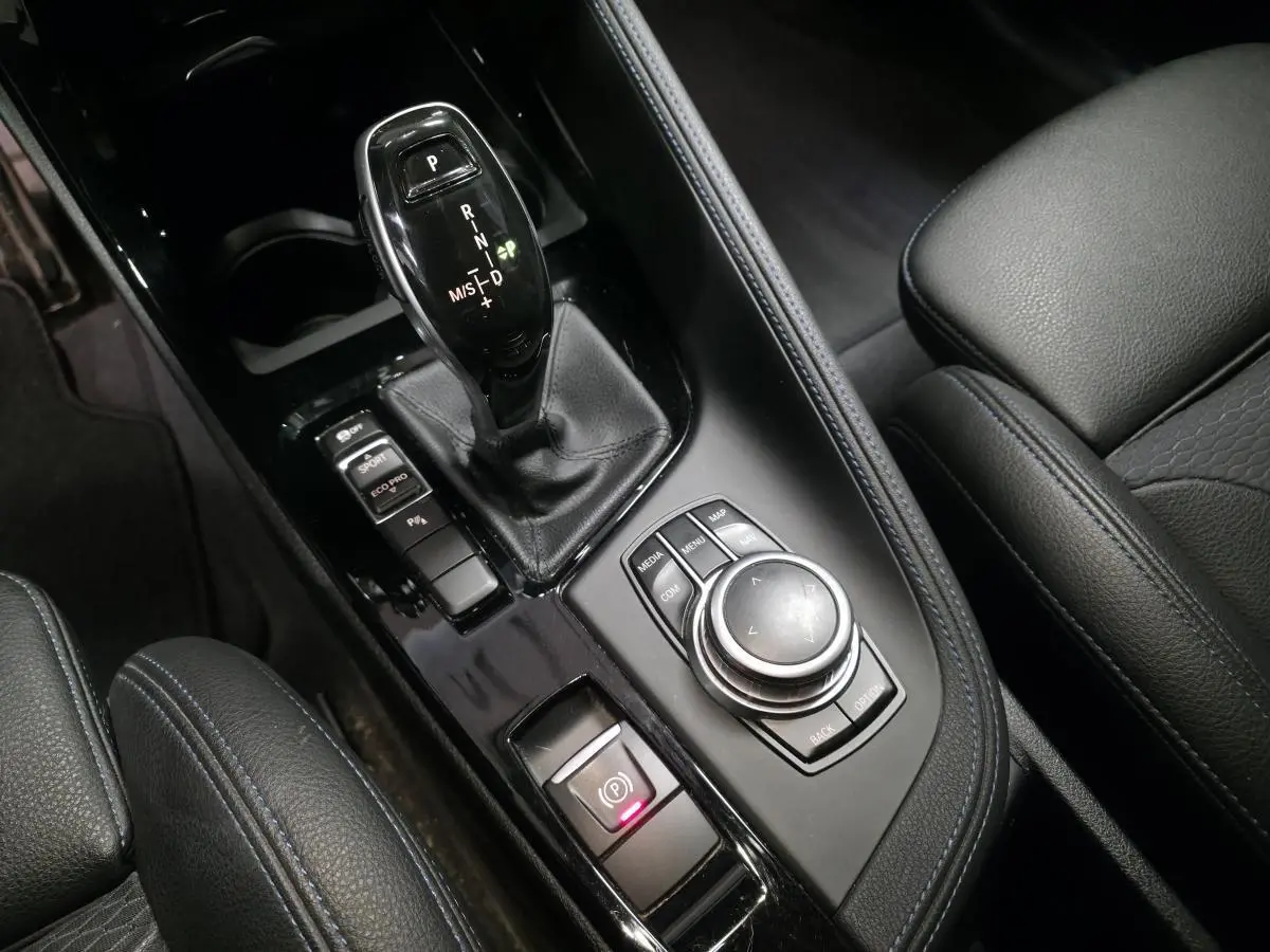 Gros plan sur la console centrale noire avec levier de vitesse automatique et commandes du BMW X2 sDrive 18d M Sport.