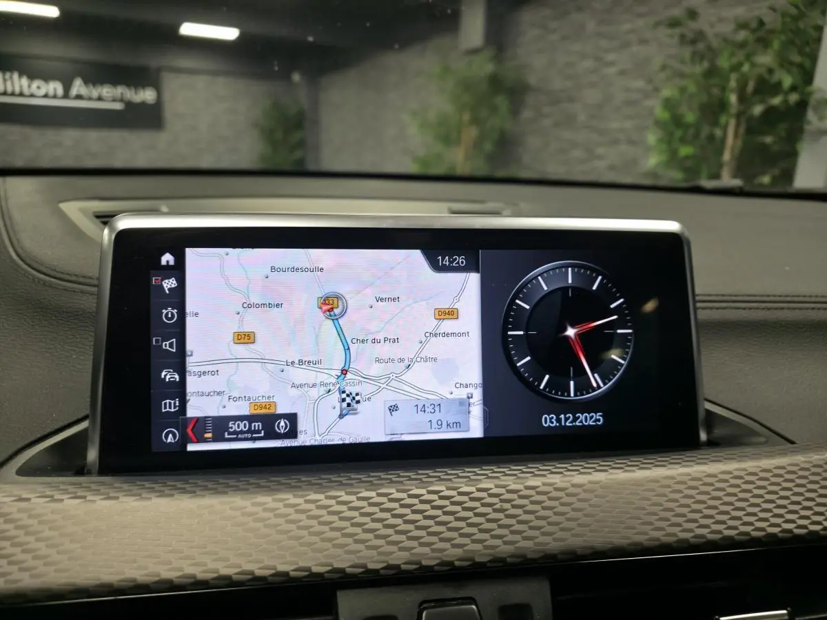 Écran central du tableau de bord BMW X2 M Sport 2021 affichant la navigation et une horloge digitale.