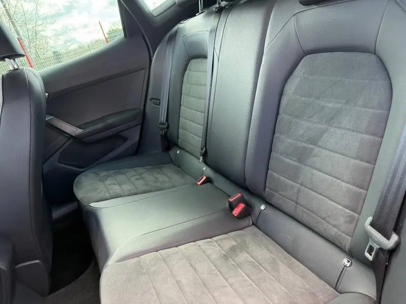 Vue intérieure des sièges arrière en tissu gris et cuir noir du SEAT Arona 2025, côté droit, avec ceintures de sécurité visibles.