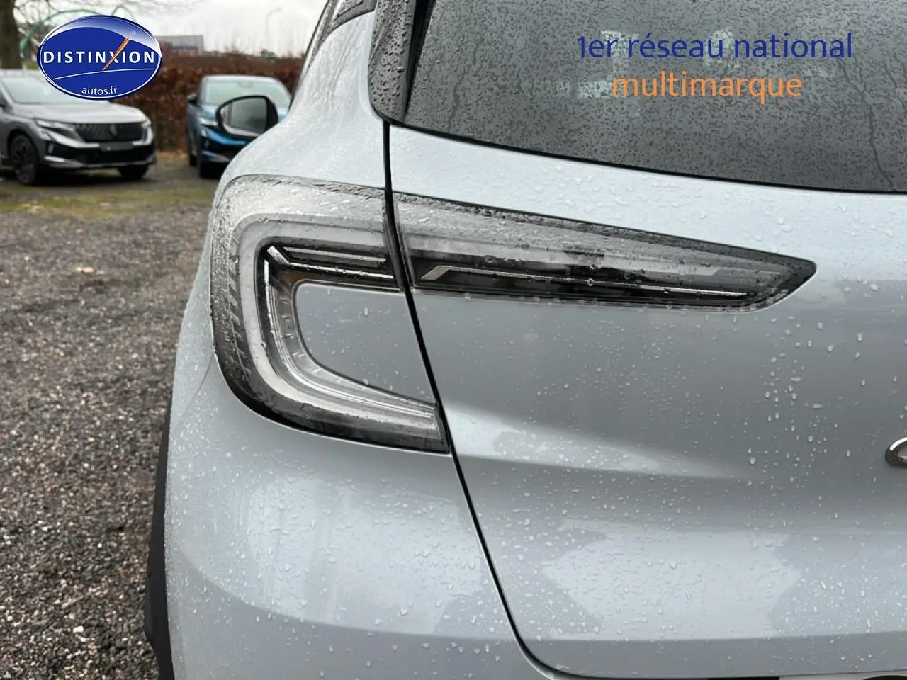Gros plan sur le feu arrière gauche du Renault Captur gris rafale 2025 sous la pluie, avec gouttes visibles.