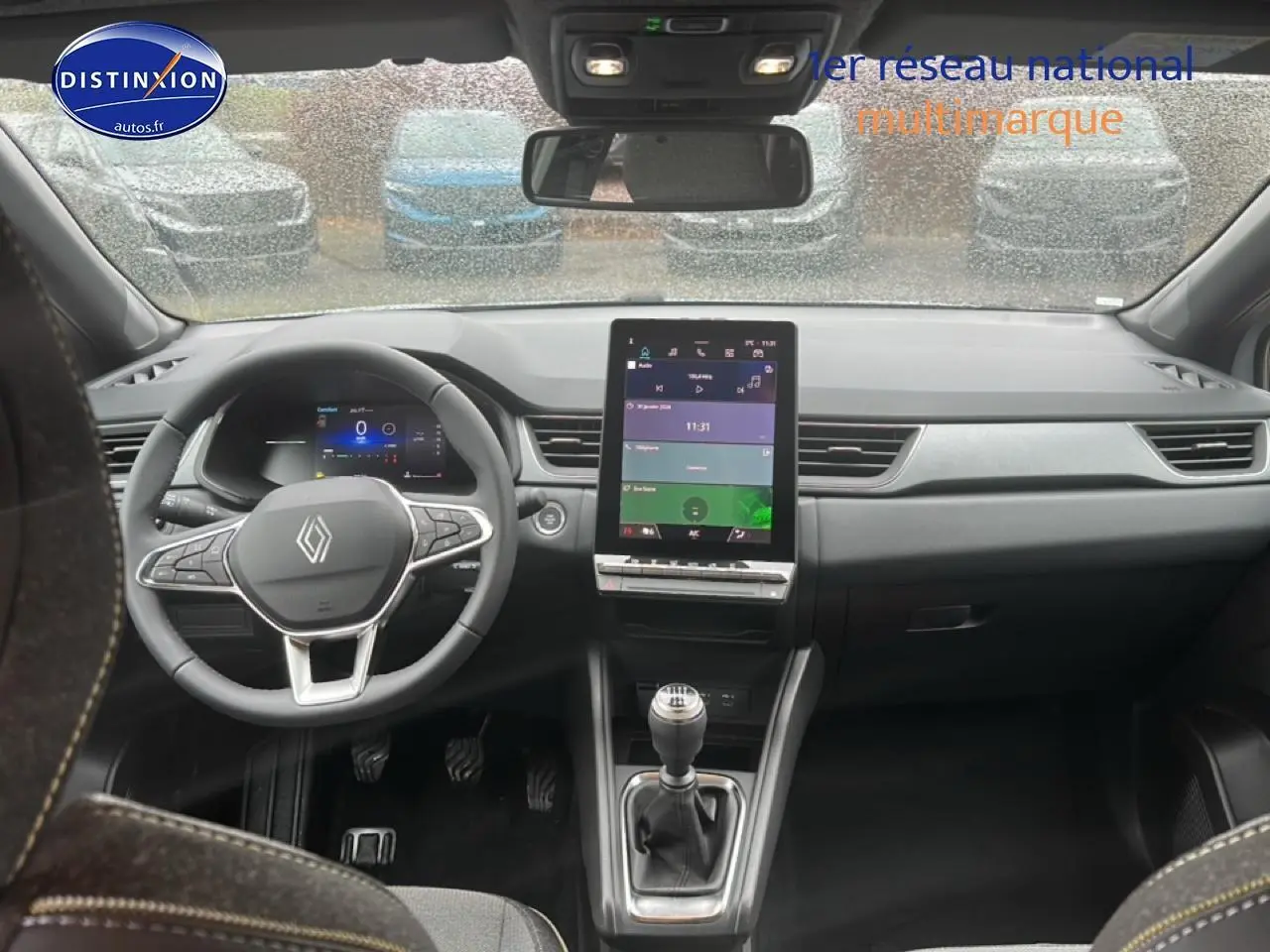 Vue intérieure avant du tableau de bord gris du Renault Captur 2025 avec écran tactile vertical et volant multifonction.