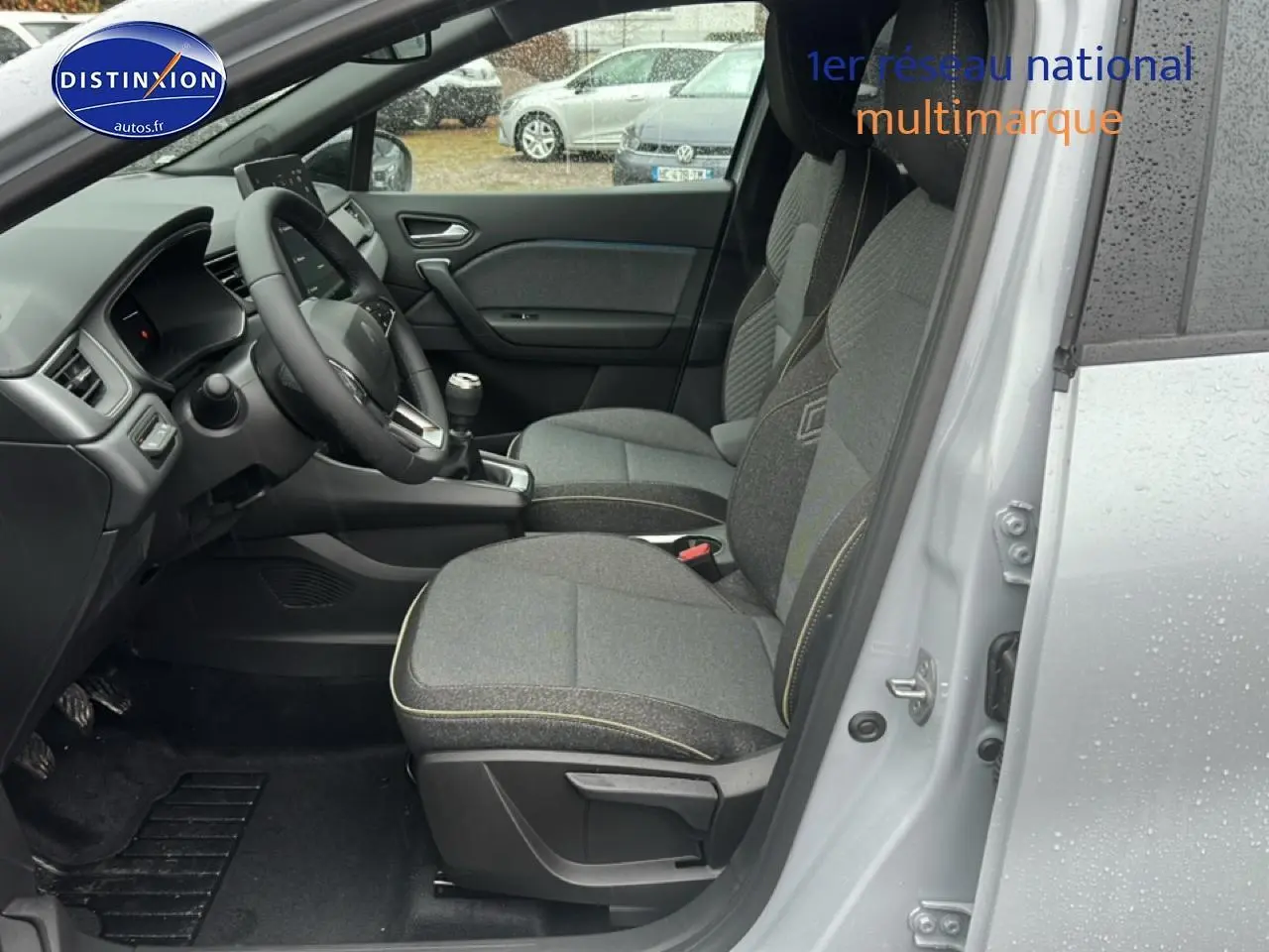 Vue intérieure côté conducteur du Renault Captur gris rafale 2025, avec sièges tissu gris et volant multifonction.