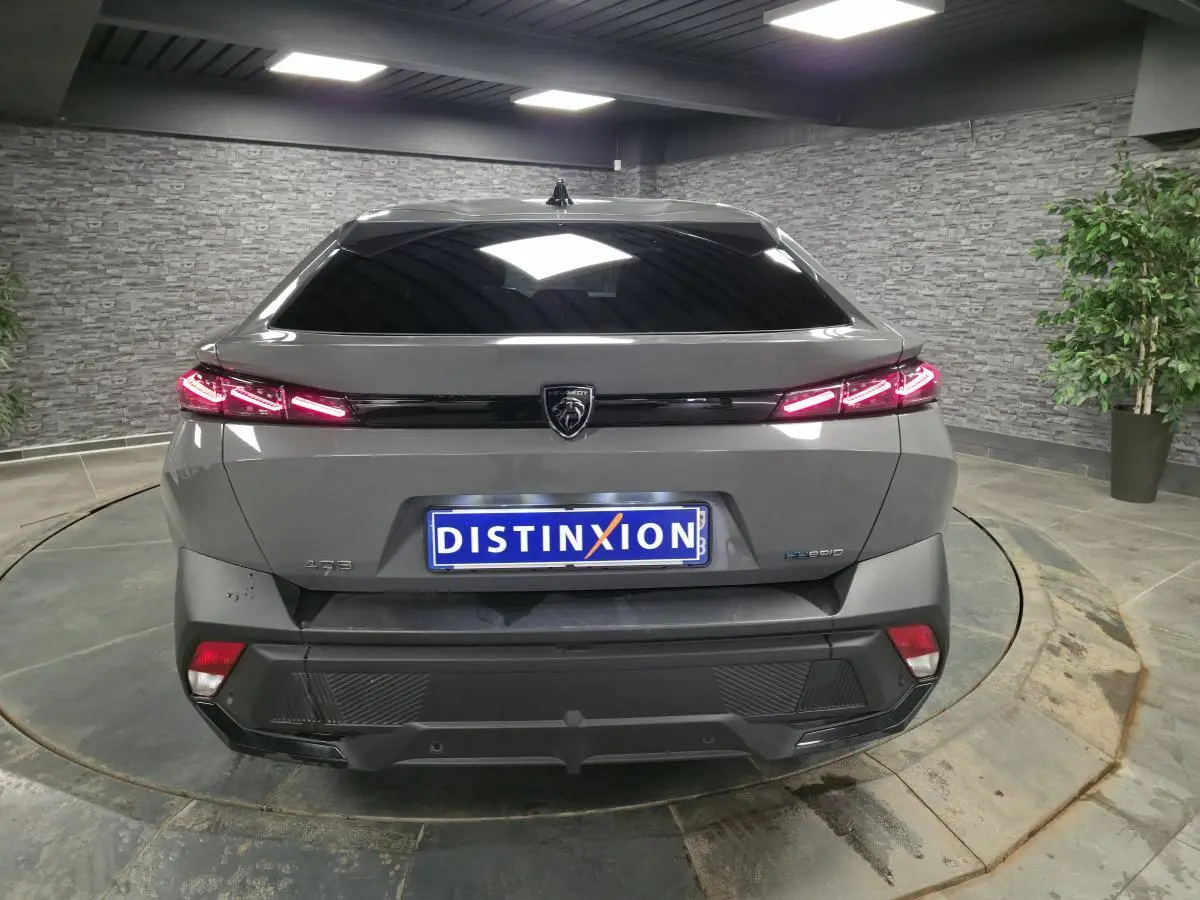 Vue arrière d'une Peugeot 408 gris métallisé avec feux arrière LED en forme de griffes et hayon électrique.