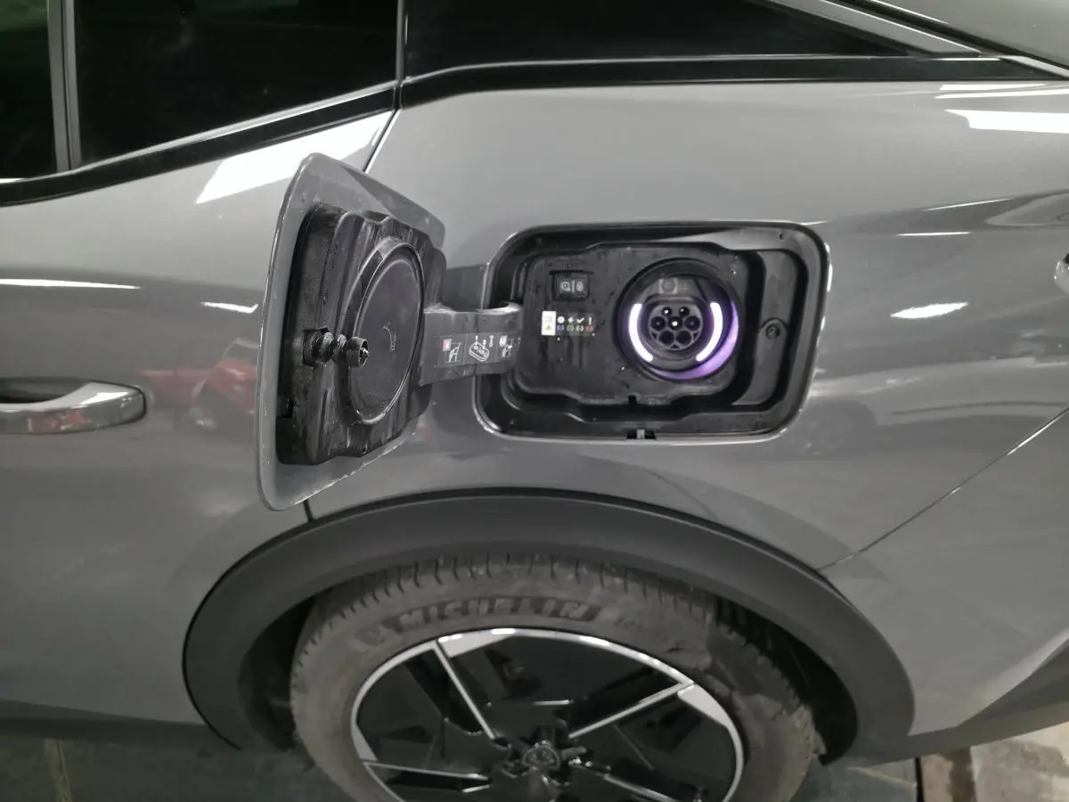 Prise de recharge ouverte côté gauche arrière sur Peugeot 408 gris métallisé avec jante alliage 19 pouces.