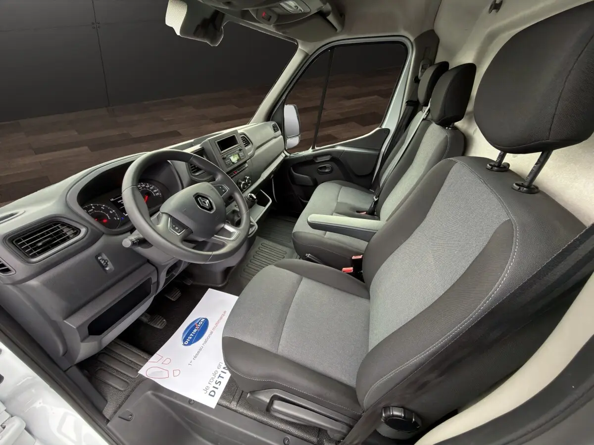 Vue intérieure côté conducteur du Renault Master blanc 2024, montrant le tableau de bord et les sièges gris.