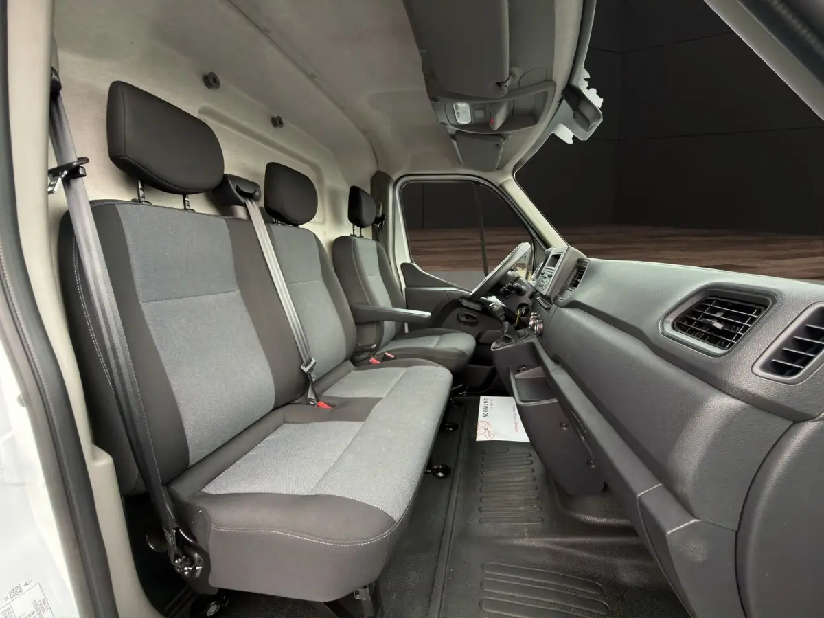 Vue intérieure côté passager du Renault Master blanc 2024, montrant les sièges gris et la planche de bord noire.