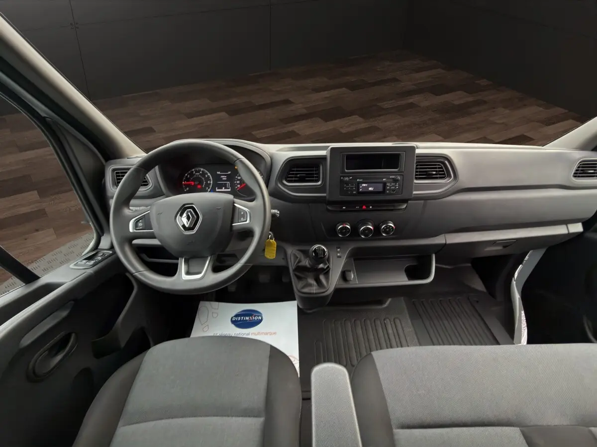 Vue intérieure avant du Renault Master 2024, tableau de bord gris avec volant multifonctions et boîte manuelle.