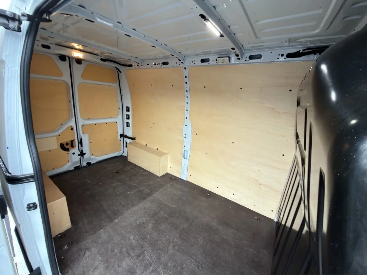Vue intérieure arrière du Renault Master blanc 2024 avec aménagement complet en bois clair dans l’espace de chargement.