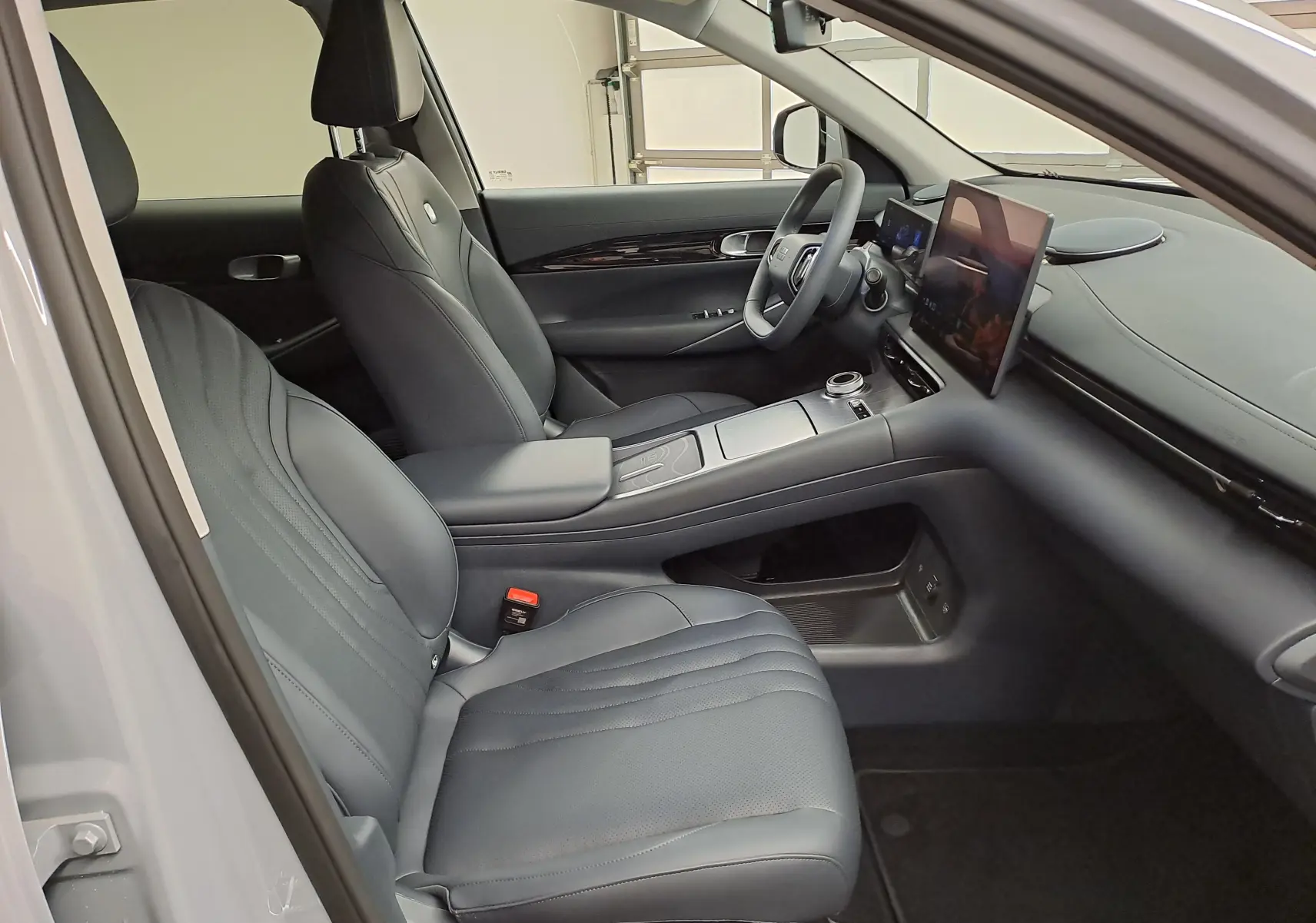 Intérieur du GEELY E5 PRO 2026 vu côté gauche, sièges cuir noirs et écran tactile central flottant.
