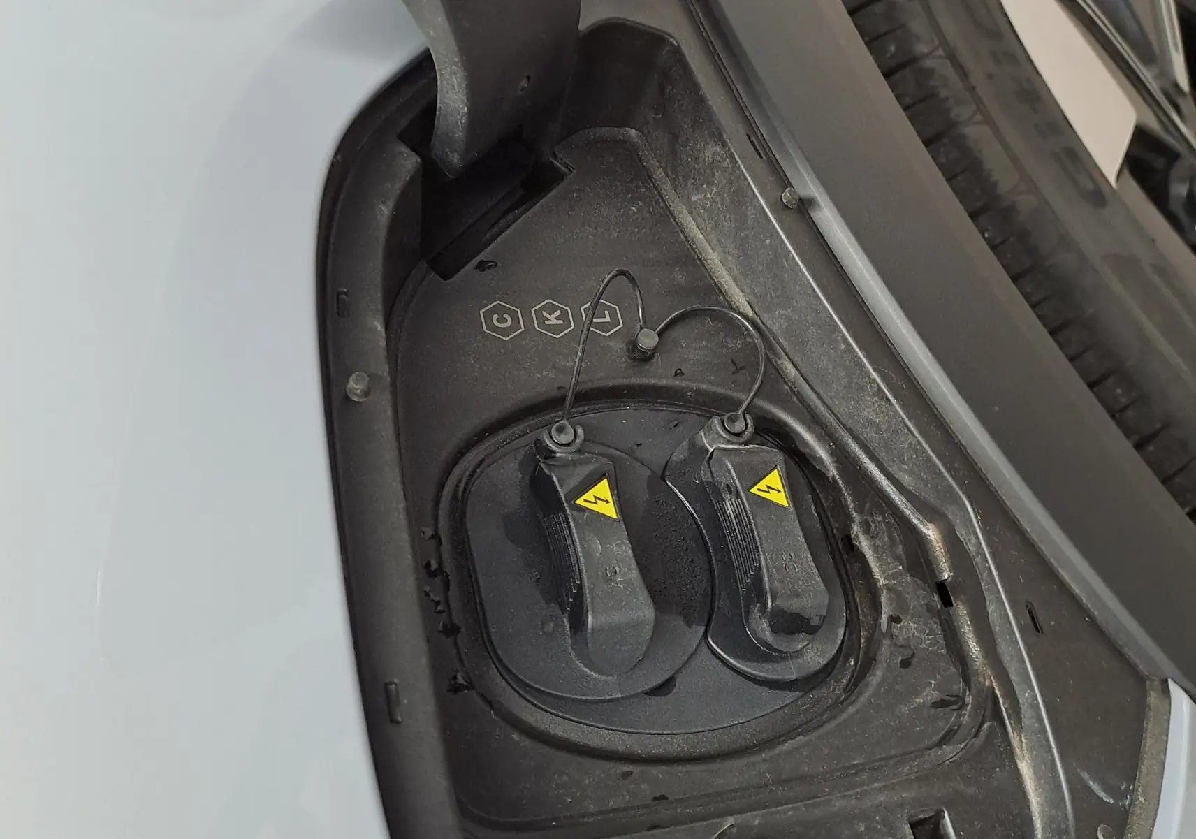 Détail de la prise de recharge électrique côté gauche du Geely E5 PRO gris Moonlight avec roue arrière visible.