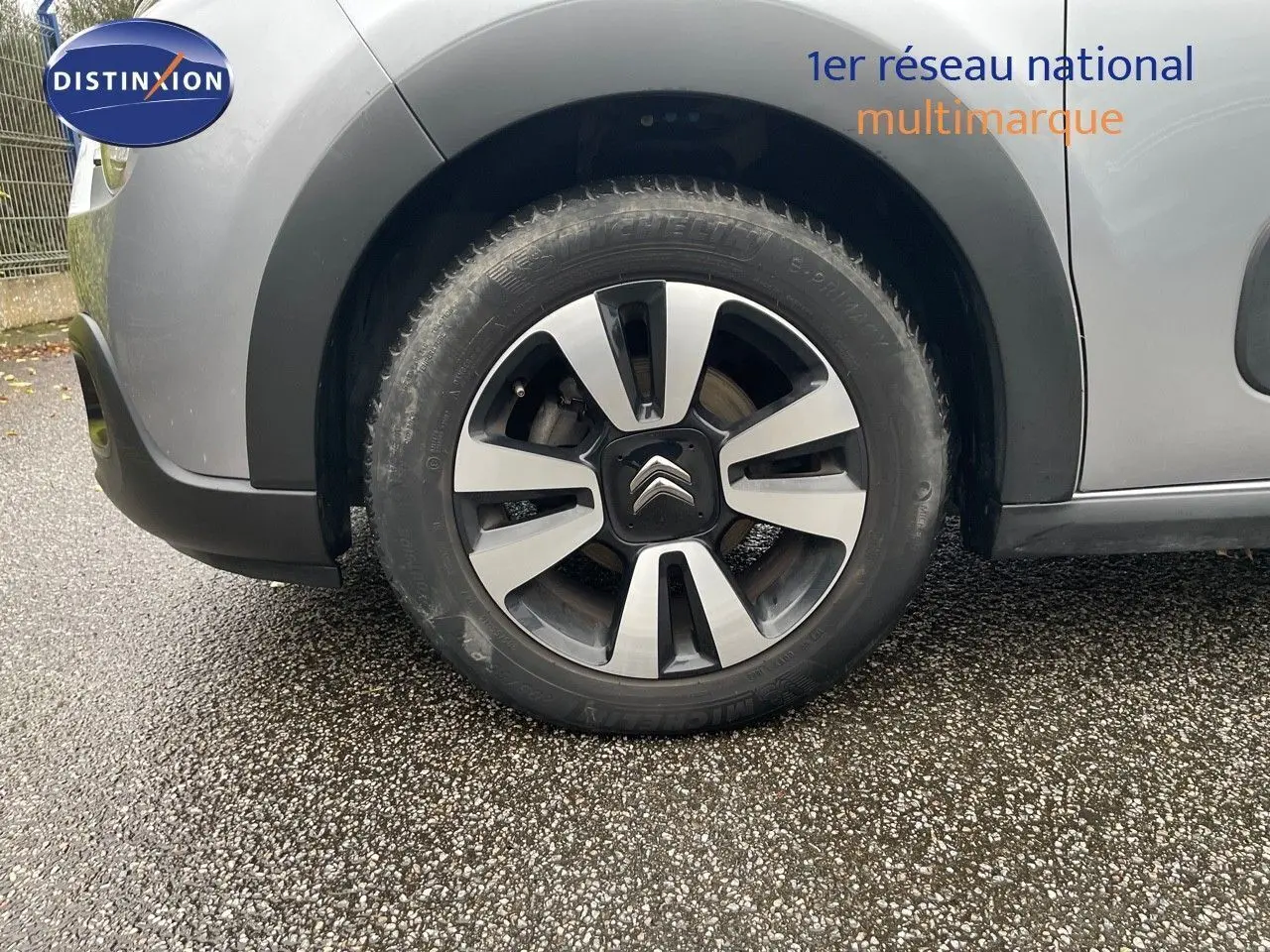 Gros plan sur la roue avant gauche d'une Citroën C3 gris acier métal avec jante alliage bicolore.
