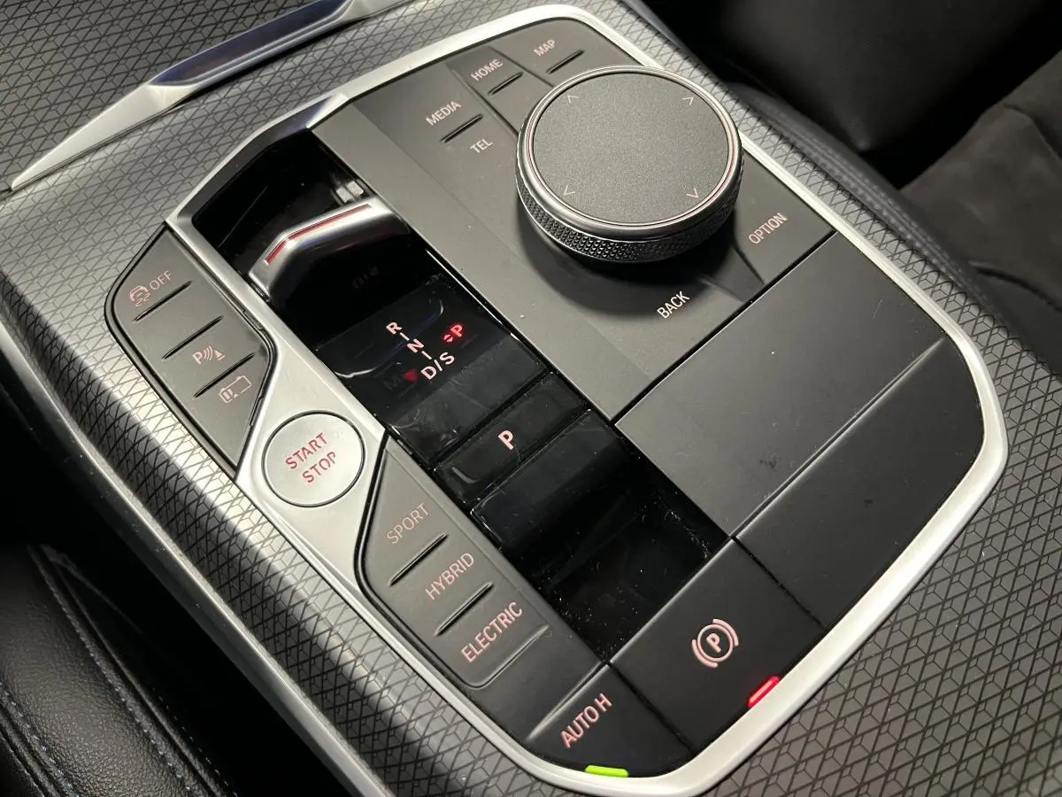 Gros plan sur la console centrale noire avec commandes de boîte auto et modes hybride de la BMW Série 3 Touring.