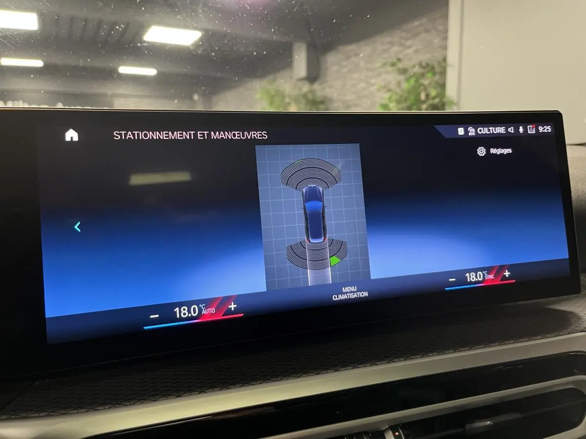 Écran central du BMW Série 3 G21 320e Touring affichant l'aide au stationnement avec vue du véhicule en bleu.