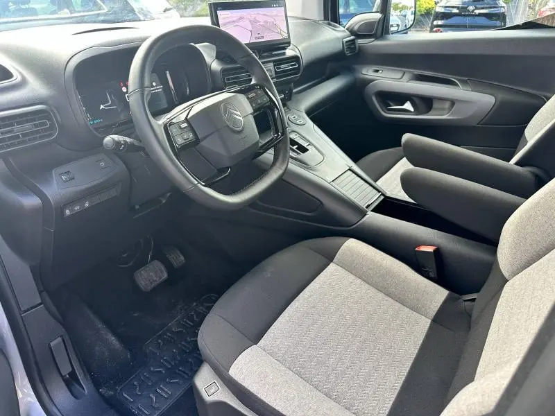 Intérieur du Citroën Berlingo XL 2024, vue côté conducteur, sièges tissu gris et tableau de bord moderne avec écran tactile.