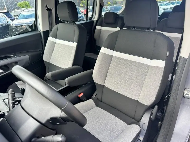 Vue intérieure du poste de conduite du Citroën Berlingo XL 2024 avec sièges gris à bandes claires et volant multifonction.