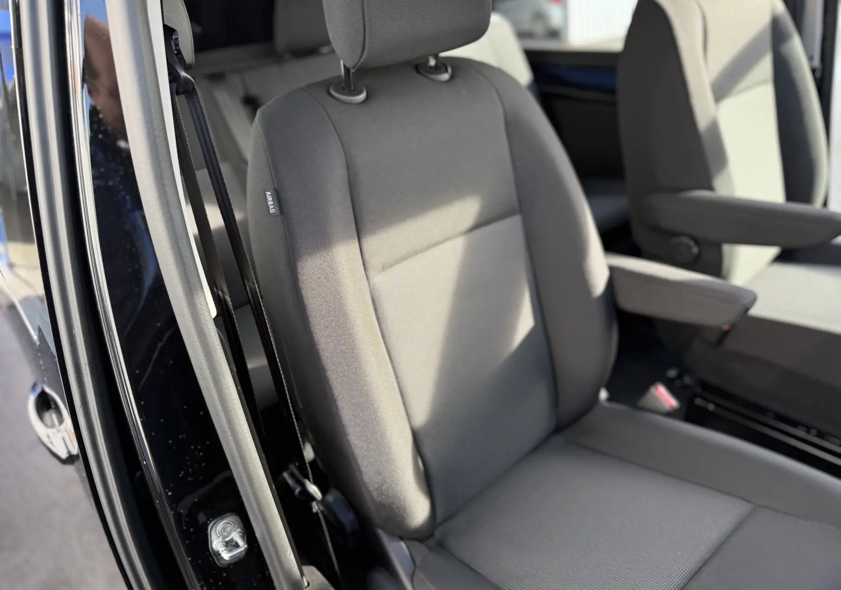 Gros plan sur les sièges avant en tissu gris du Citroën Jumpy Cabine Approfondie XL noir perla, avec ceinture de sécurité visible.