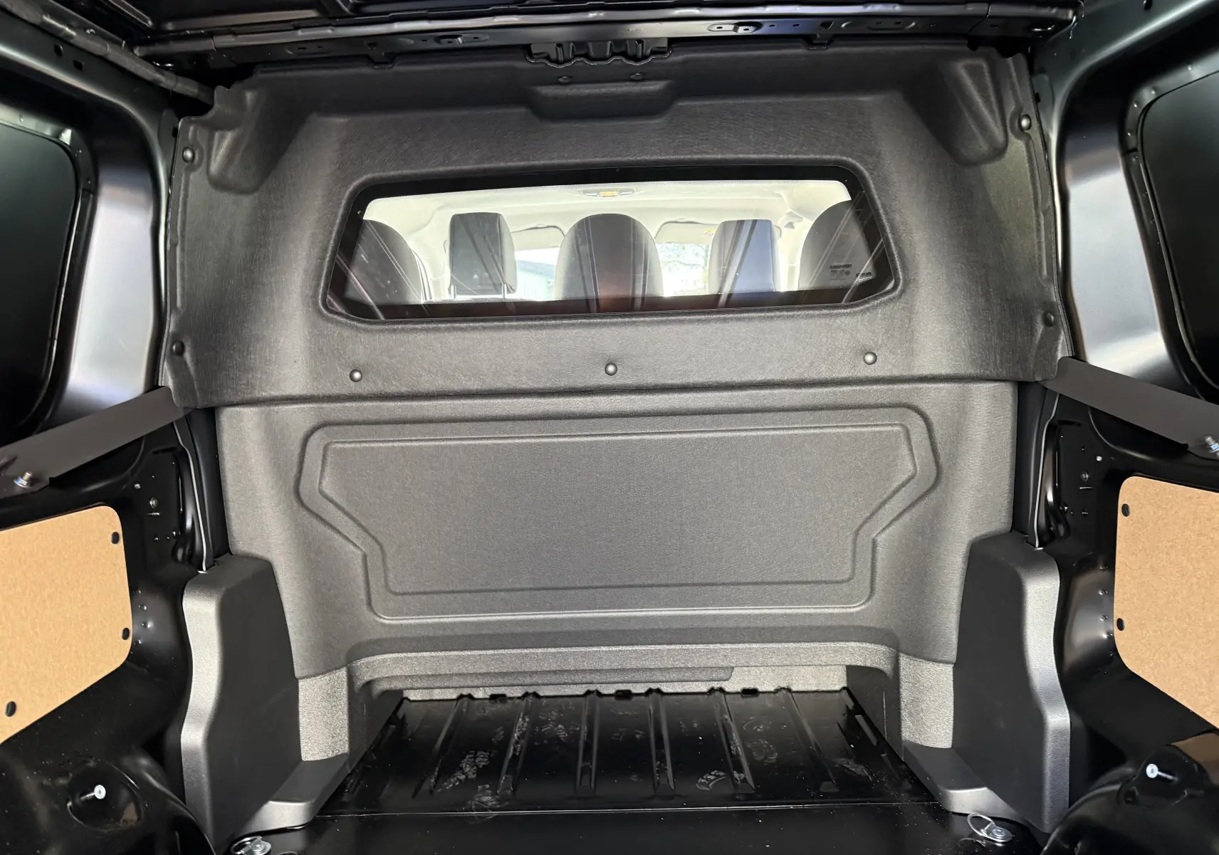 Intérieur de la cabine approfondie noire du Citroën Jumpy XL 2025, vue du compartiment de chargement vers les sièges arrière.