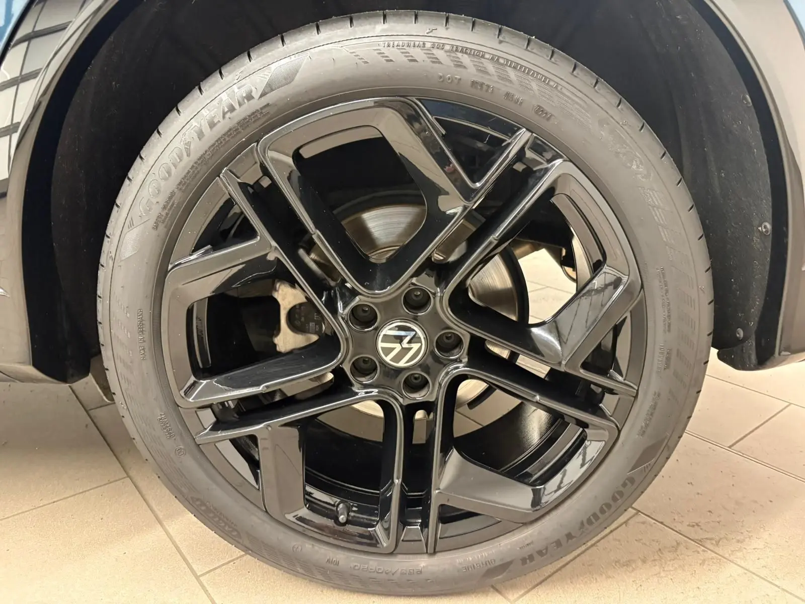 Gros plan sur la jante noire 20'' York en alliage du Volkswagen Tiguan Nightshade Blue, avec pneu Goodyear.