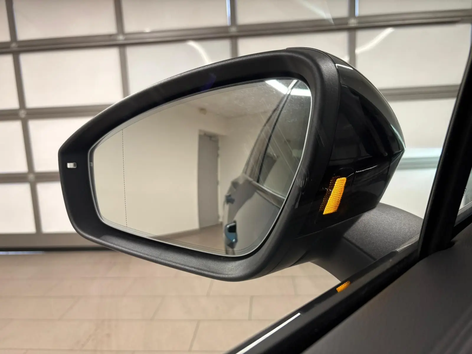 Rétroviseur côté droit du Volkswagen Tiguan Nightshade Blue 2024 avec clignotant latéral orange allumé.