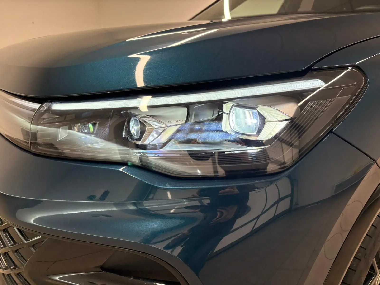 Gros plan sur le phare avant droit du Volkswagen Tiguan 2024 en Nightshade Blue avec éclairage LED IQ.Light.