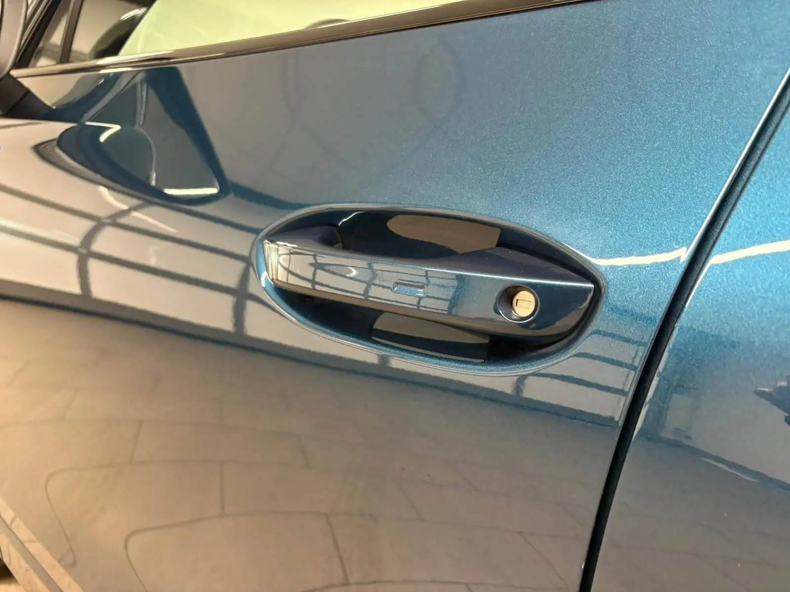 Poignée de porte côté gauche en gros plan sur Volkswagen Tiguan 2024 Nightshade Blue avec reflet intérieur.