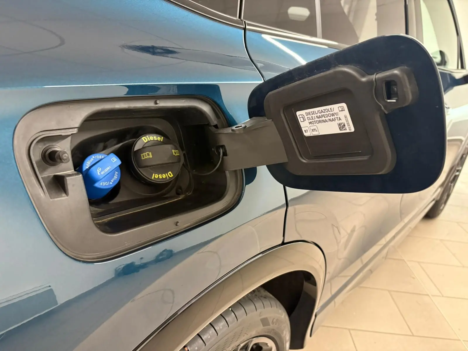Gros plan sur la trappe à carburant ouverte côté gauche d’un Volkswagen Tiguan Nightshade Blue 2024 diesel.