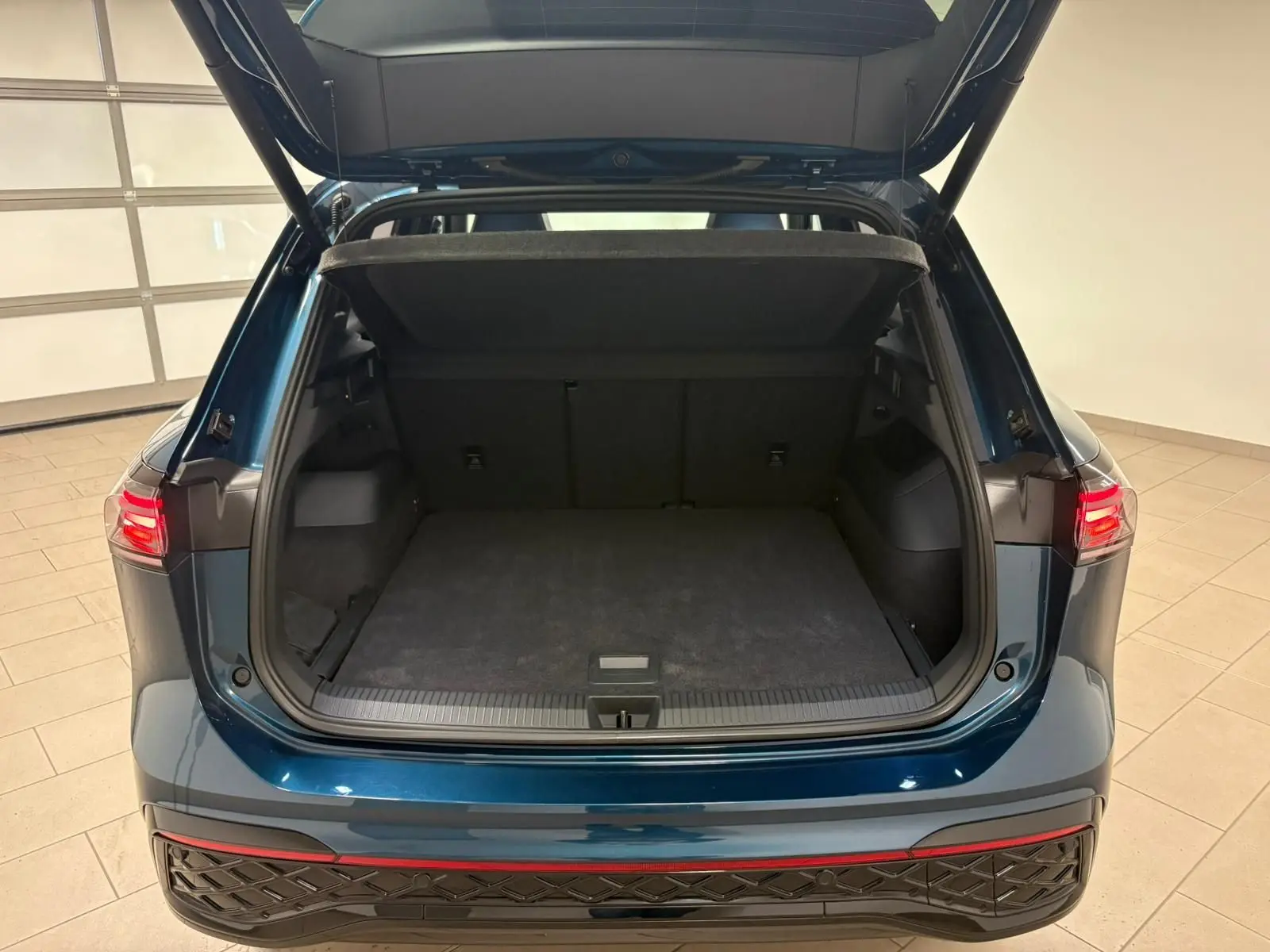 Vue arrière du Volkswagen Tiguan 2024 Nightshade Blue avec coffre ouvert et hayon électrique visible.
