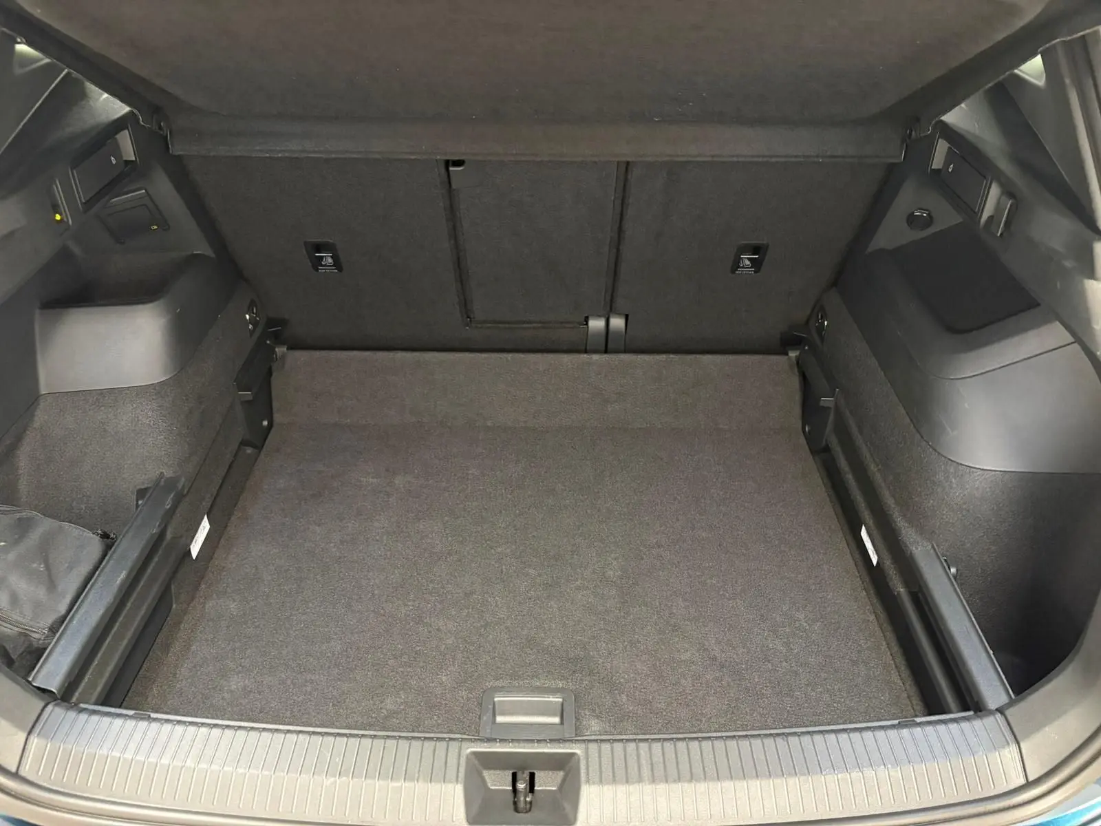 Coffre spacieux du Volkswagen Tiguan 2024 en Nightshade Blue, vue intérieure sans chargement, avec revêtement noir.