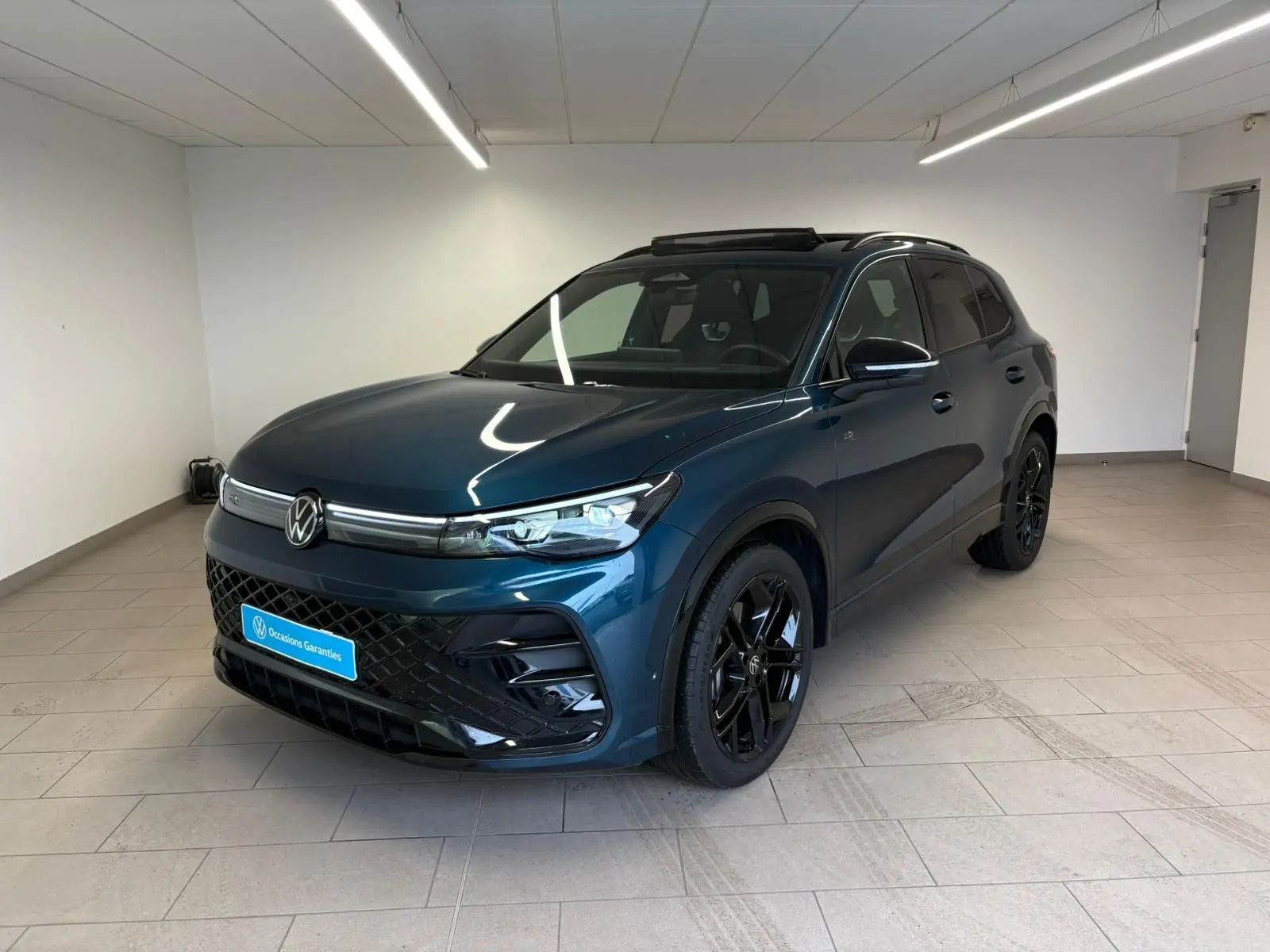 Volkswagen Tiguan 2.0 TDI 150 DSG7 en Nightshade Blue, vue 3/4 avant avec jantes noires et toit ouvrant panoramique.