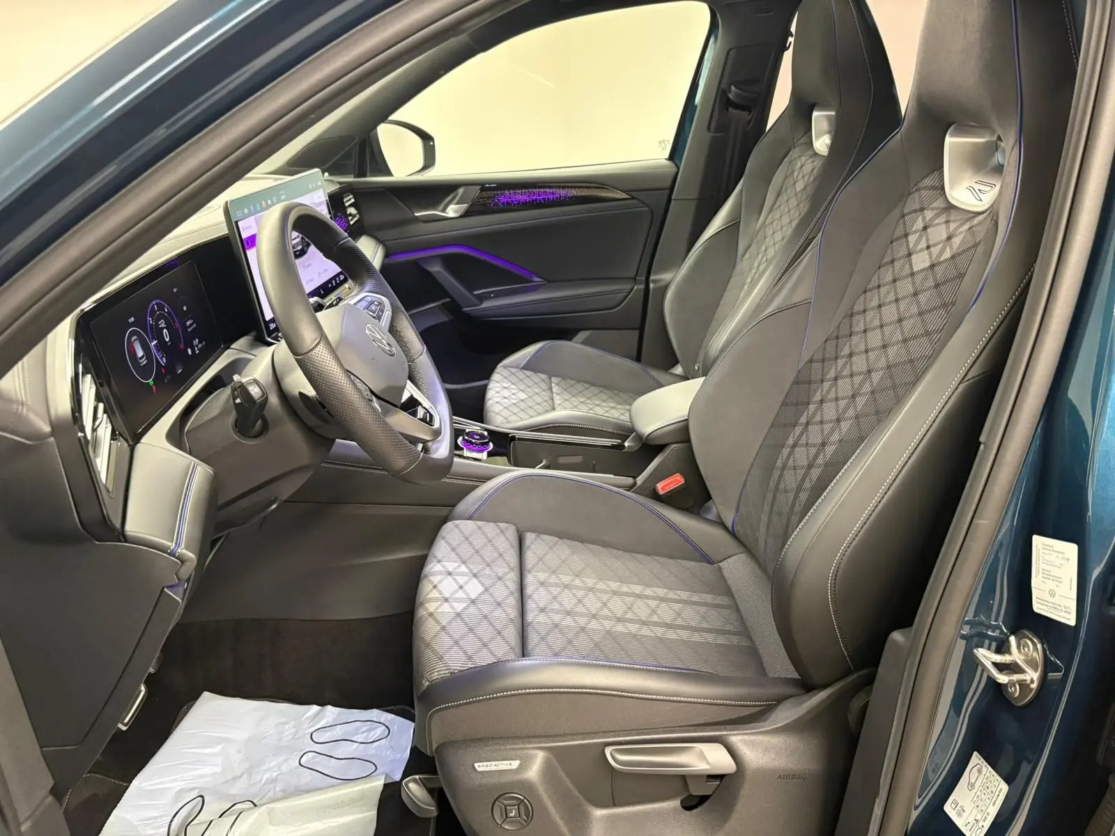 Vue intérieure côté conducteur du Volkswagen Tiguan 2024 Nightshade Blue, sièges sport avec surpiqûres bleues et tableau de bord numérique.