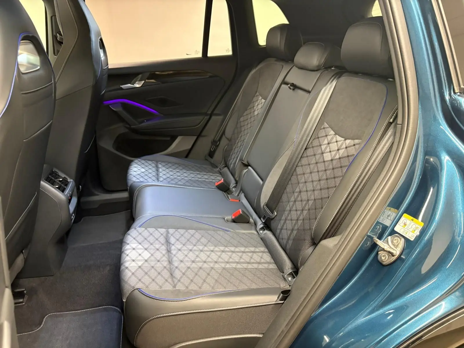 Vue intérieure arrière côté droit du Volkswagen Tiguan 2024 Nightshade Blue avec sièges en tissu et cuir noir à surpiqûres bleues.