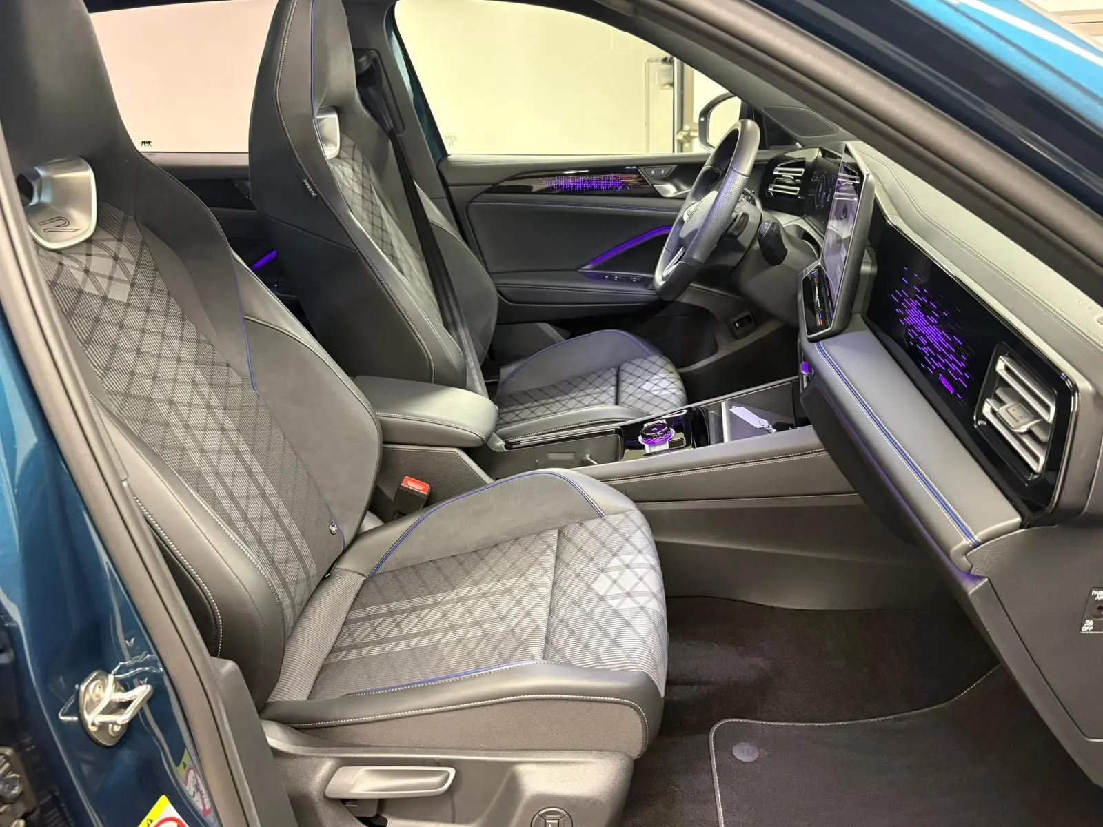 Vue intérieure côté conducteur du Volkswagen Tiguan 2024 Nightshade Blue, avec sièges en cuir et éclairage d'ambiance violet.