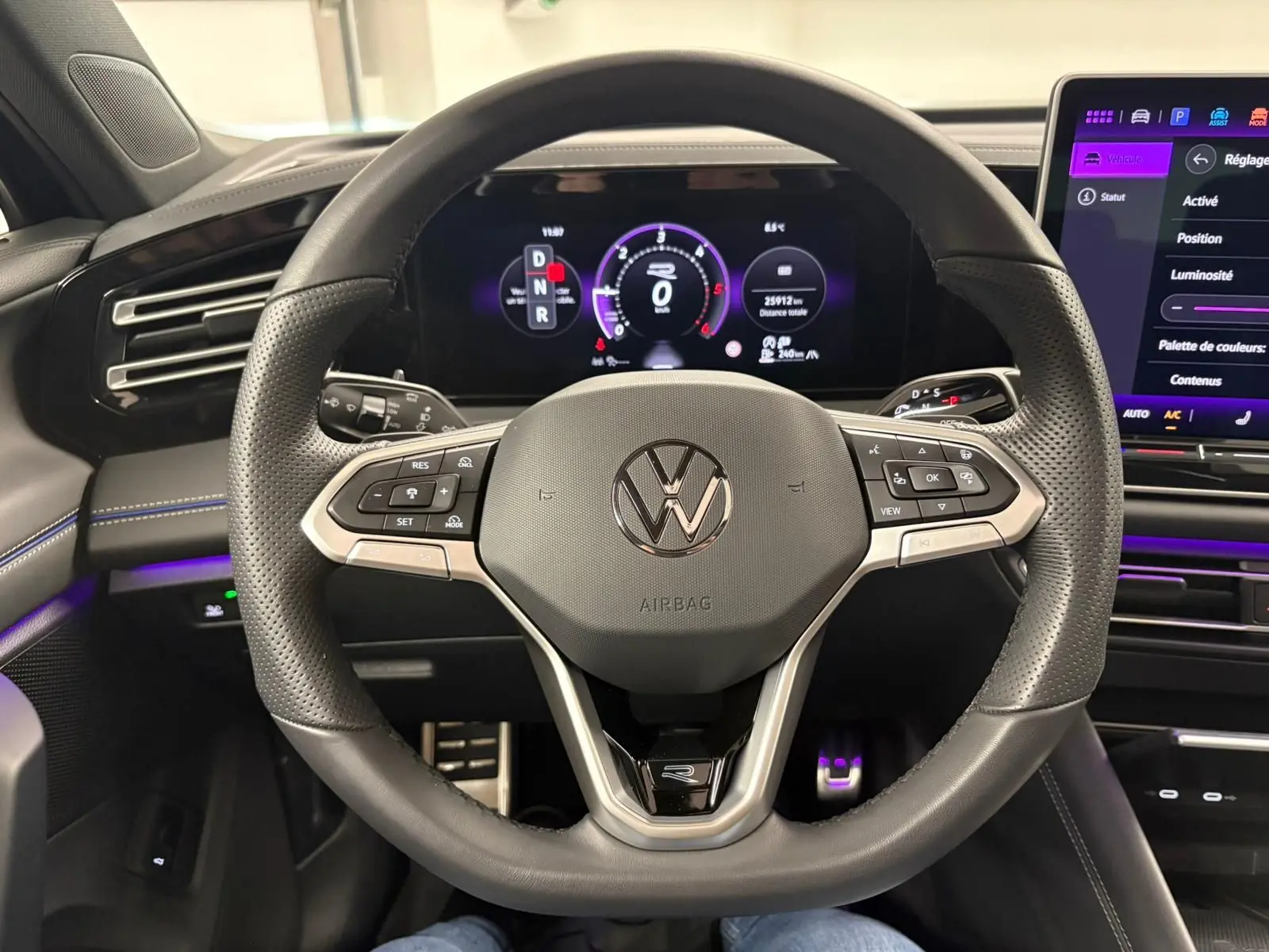 Vue rapprochée du volant en cuir perforé du Volkswagen Tiguan 2024 avec tableau de bord numérique et écran tactile.