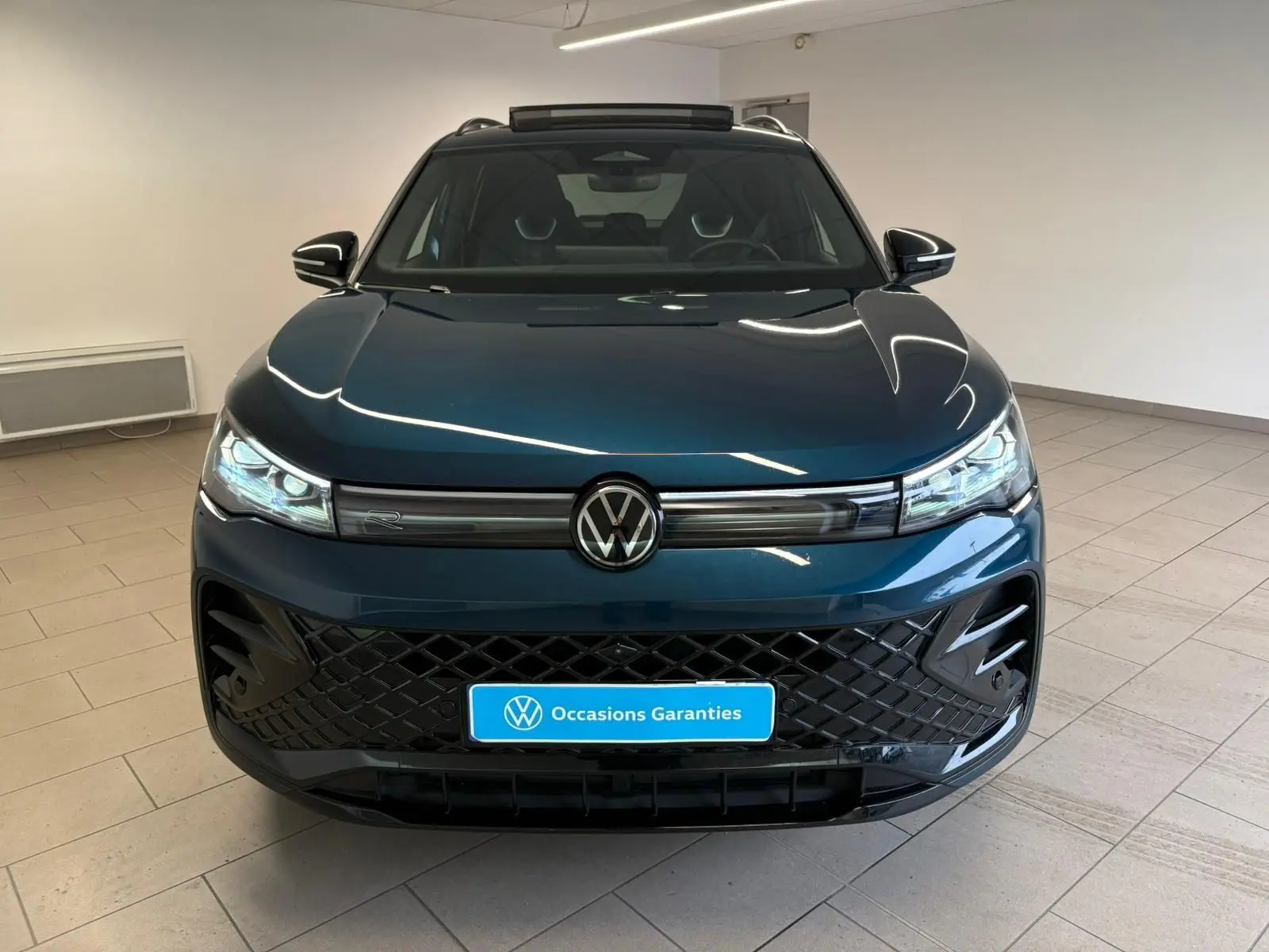 Vue avant d'un Volkswagen Tiguan 2024 Nightshade Blue avec calandre noire et phares LED matriciels allumés.
